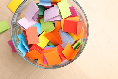 Photo of Jar with colorful pieces of paper on wooden table, top view