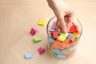 Photo of Woman taking paper with message out of jar at wooden table, closeup. Space for text