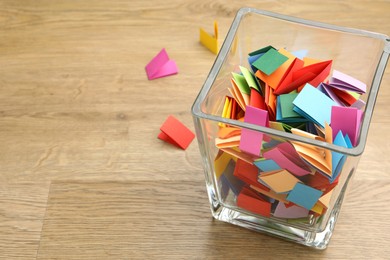 Photo of Jar with colorful pieces of paper on wooden table, closeup. Space for text
