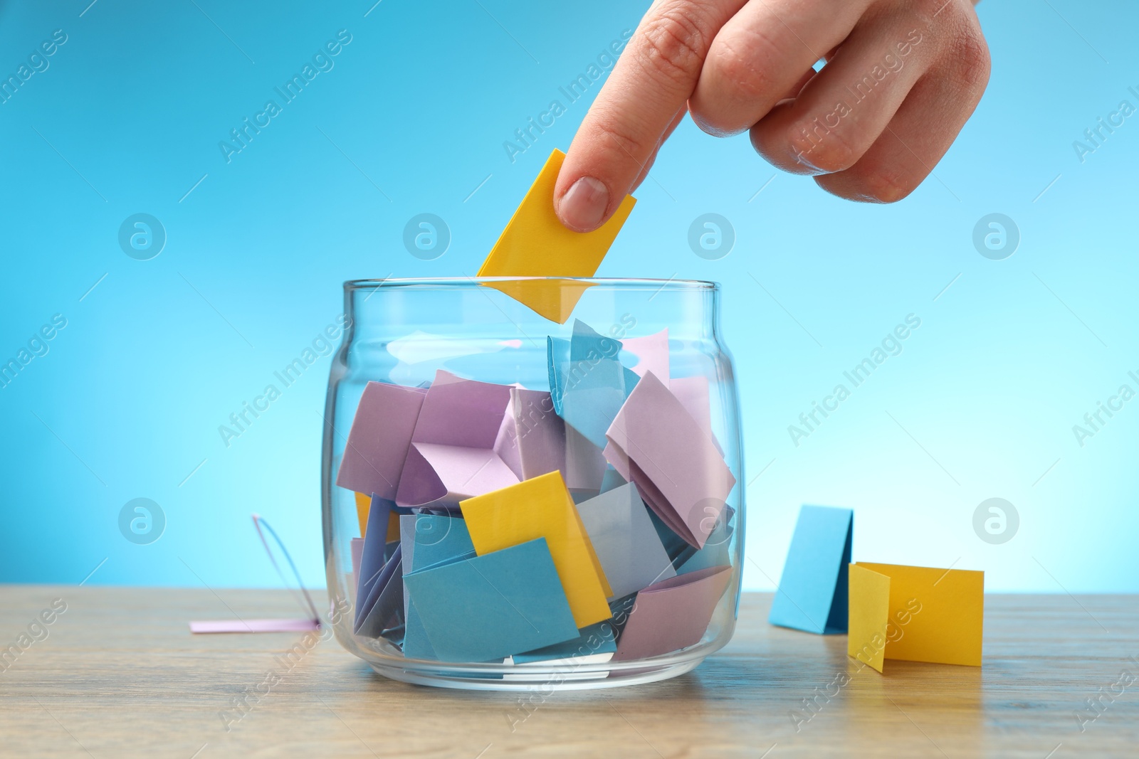 Photo of Woman taking paper with message out of jar at wooden table, closeup