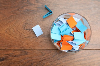 Photo of Jar with colorful pieces of paper on wooden table, top view. Space for text