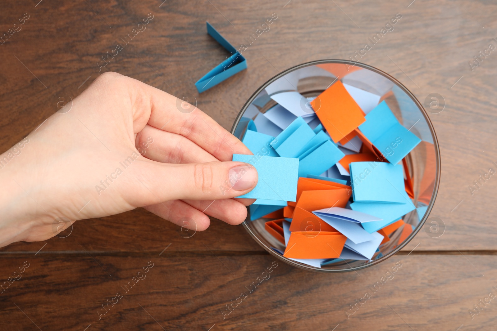 Photo of Woman taking paper with message out of jar at wooden table, top view
