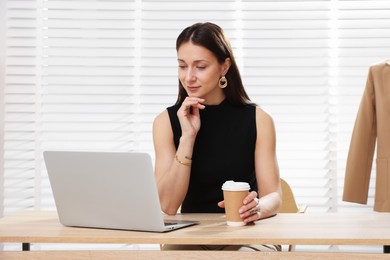 Photo of Professional stylist having online consultation with client via laptop at desk indoors