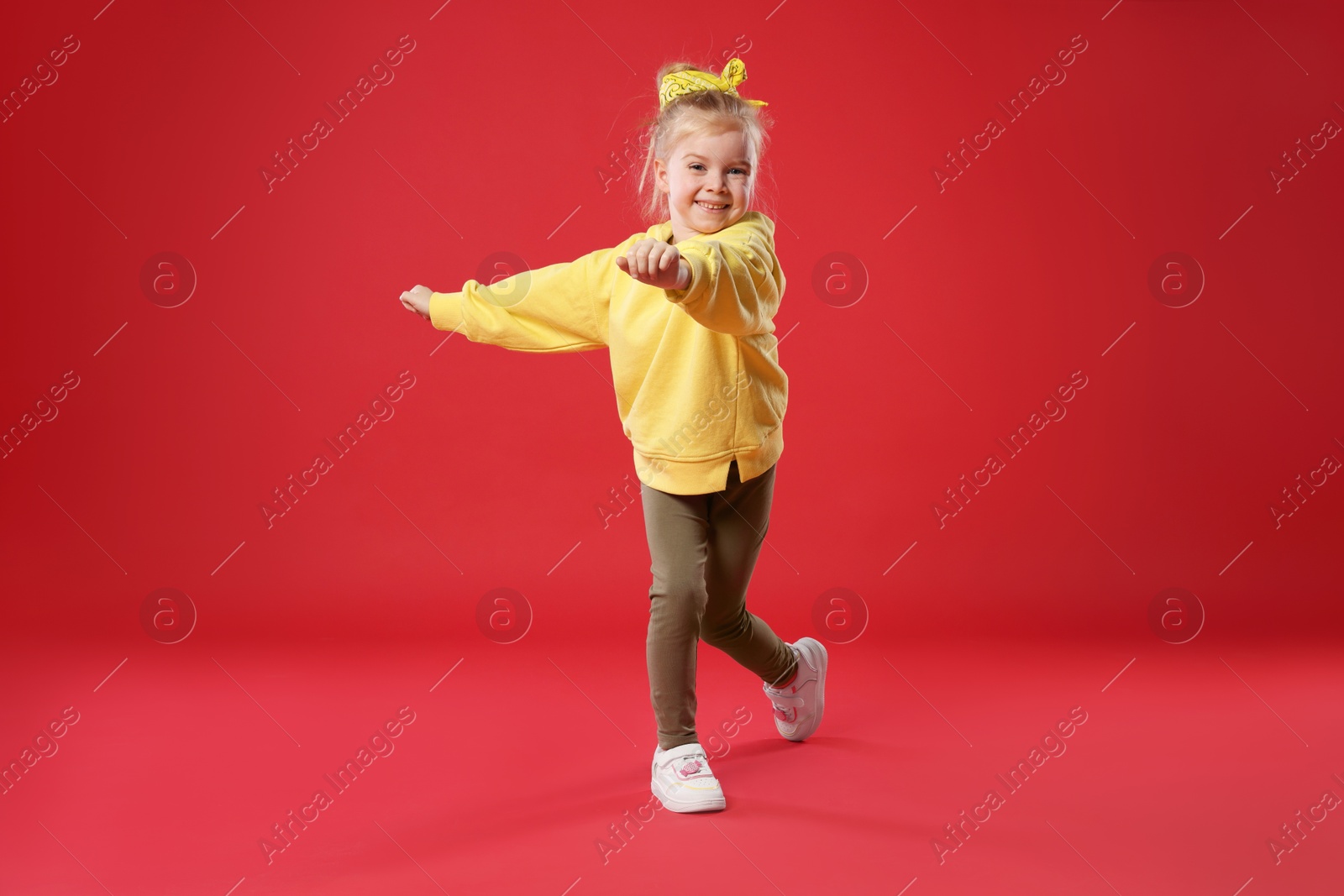 Cute little girl dancing on red background Photo of Cute little girl dancing on red background