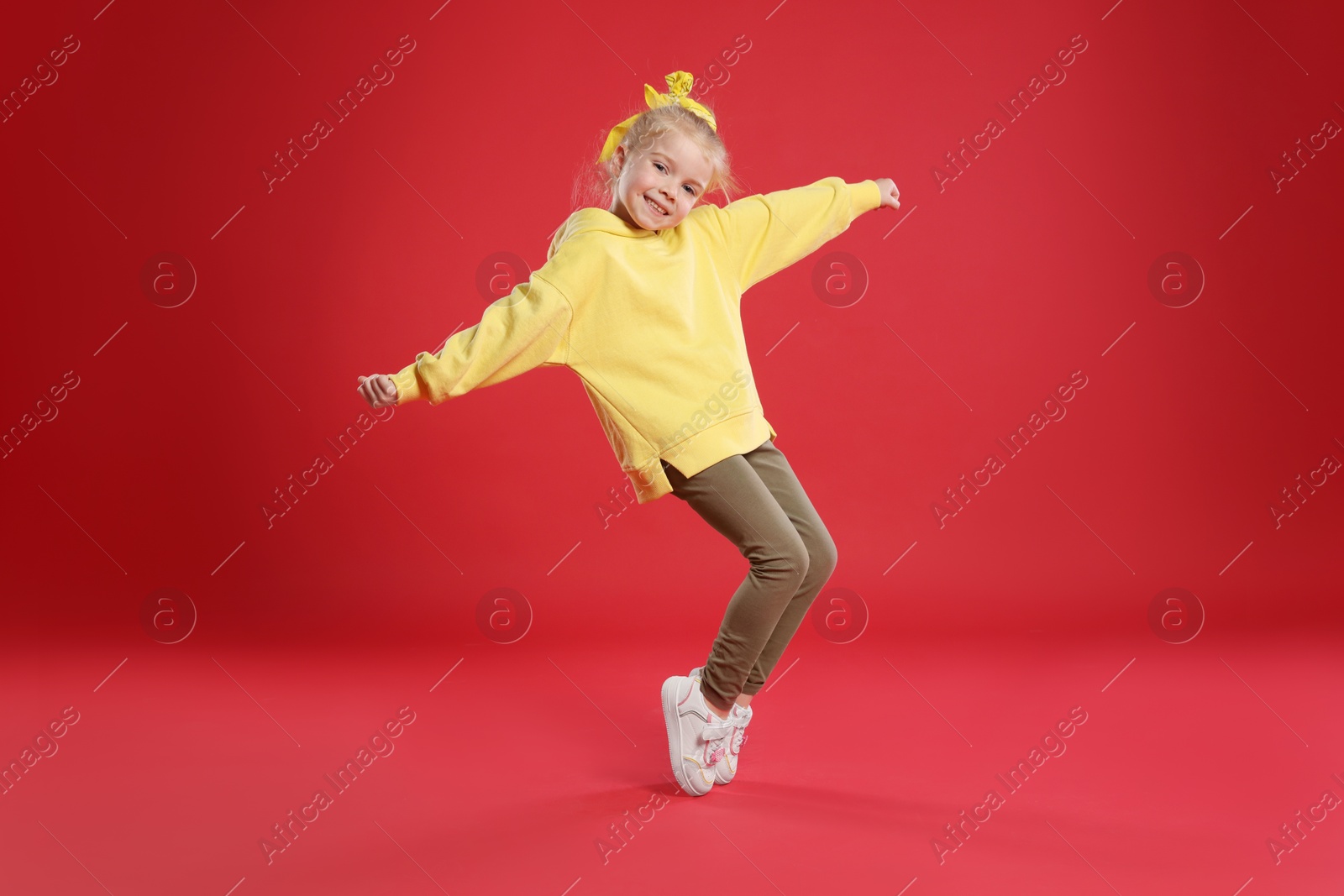 Cute little girl dancing on red background Photo of Cute little girl dancing on red background