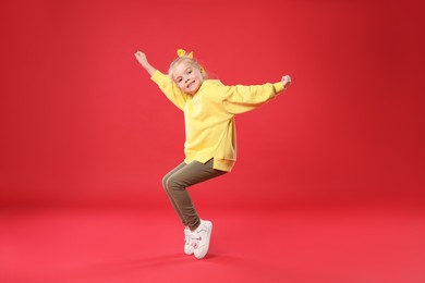 Photo of Cute little girl dancing on red background
