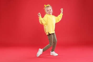 Photo of Cute little girl dancing on red background