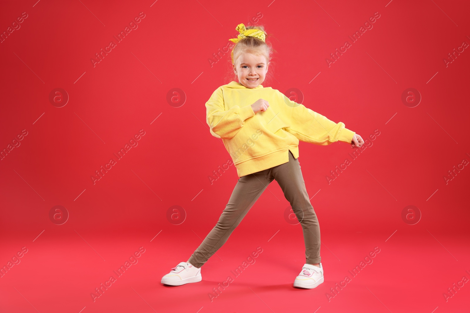 Cute little girl dancing on red background Photo of Cute little girl dancing on red background