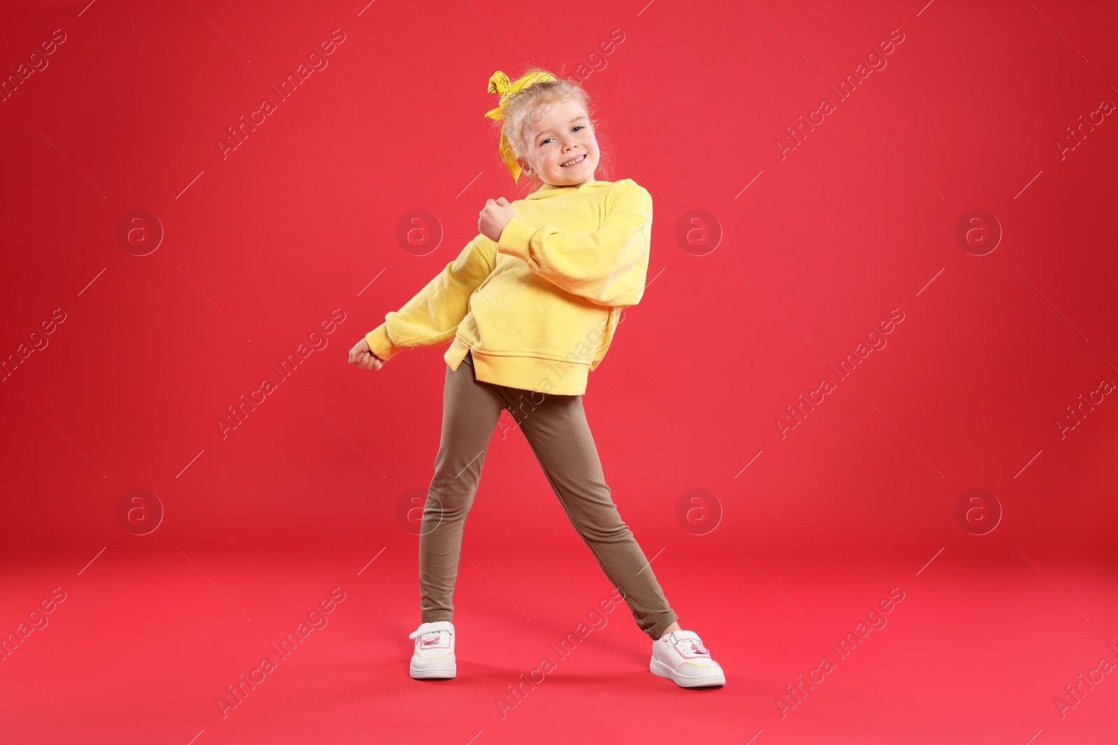 Cute little girl dancing on red background Photo of Cute little girl dancing on red background