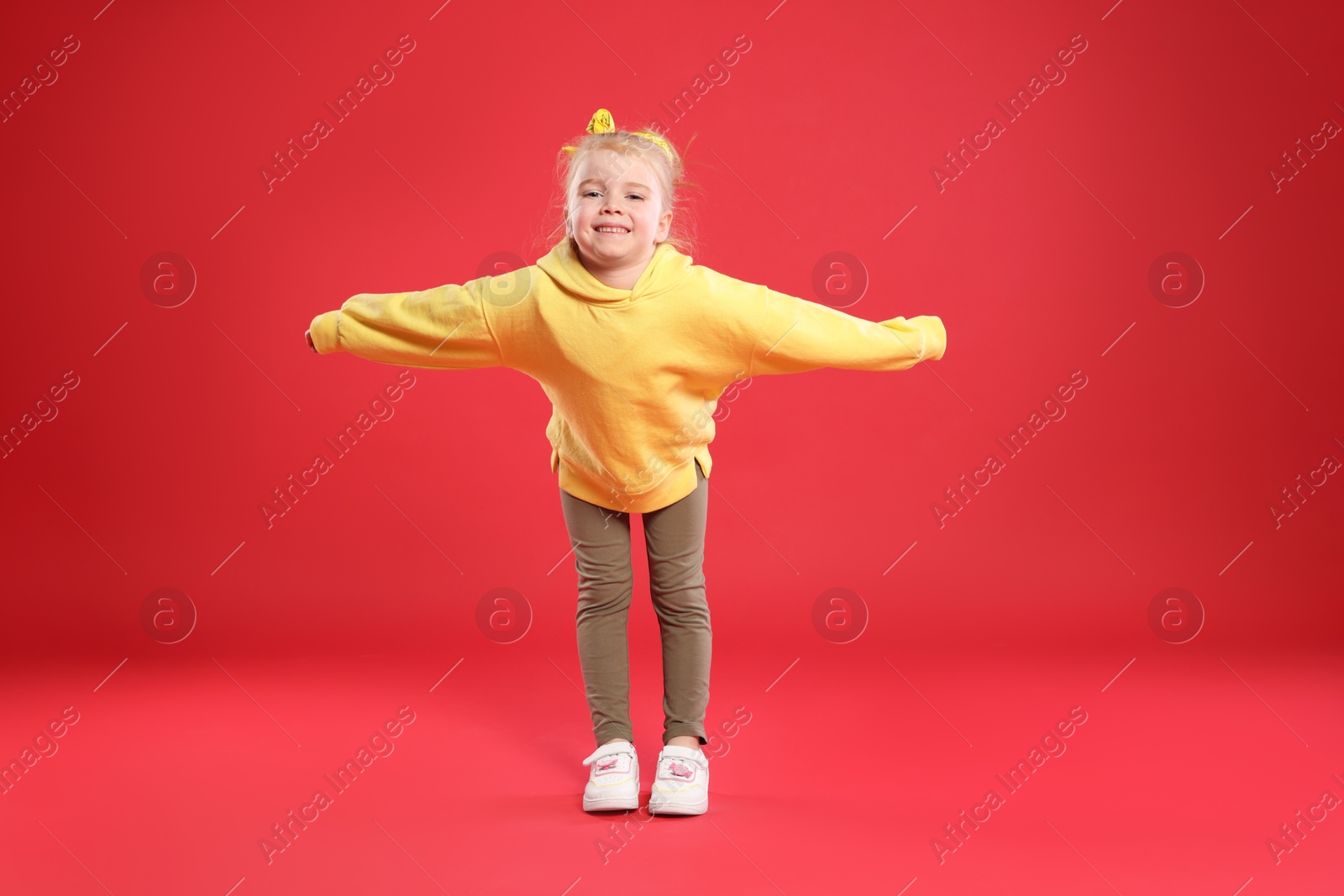 Cute little girl dancing on red background Photo of Cute little girl dancing on red background