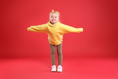 Photo of Cute little girl dancing on red background