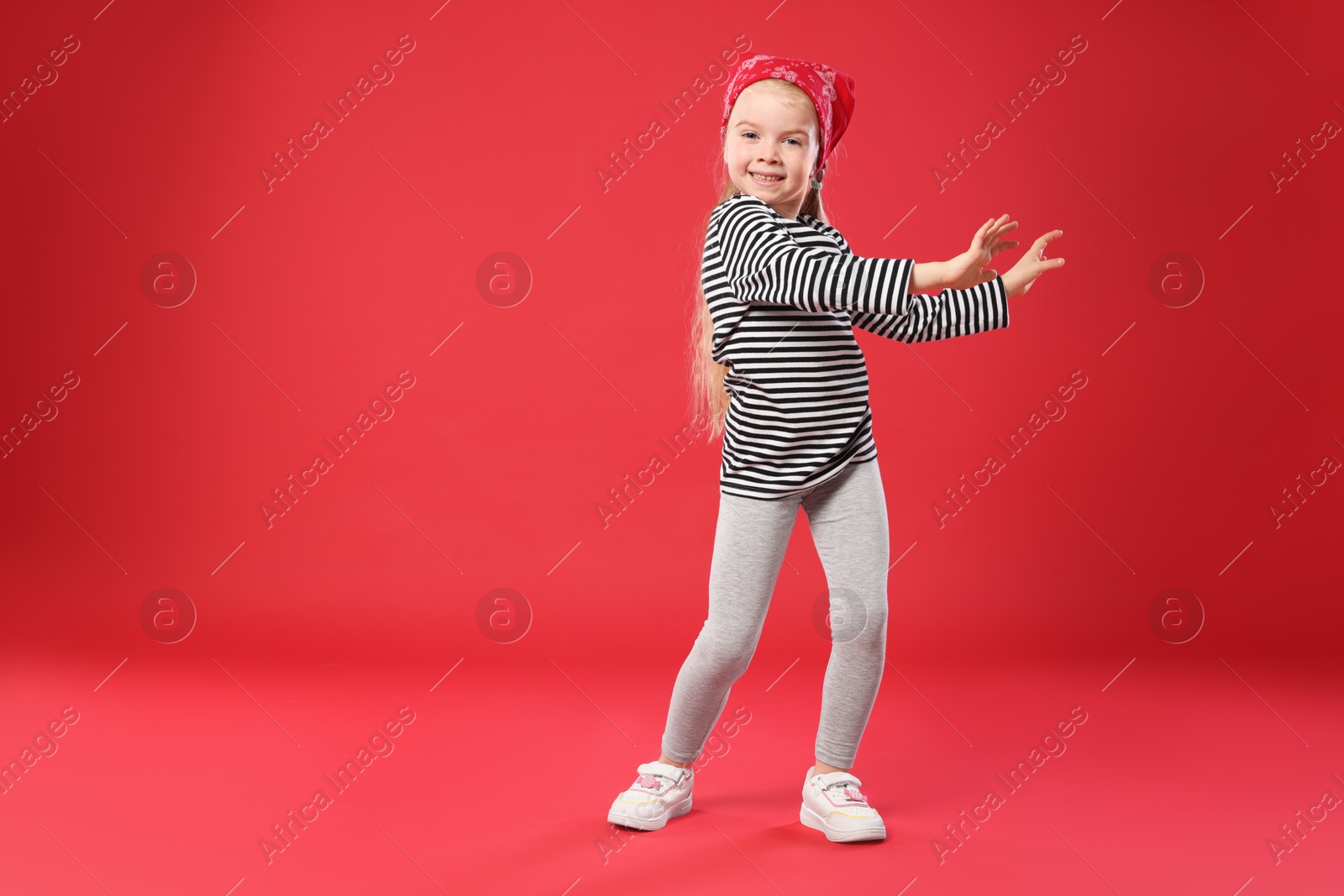 Cute little girl dancing on red background, space for text Photo of Cute little girl dancing on red background, space for text