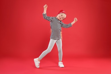 Photo of Cute little girl dancing on red background