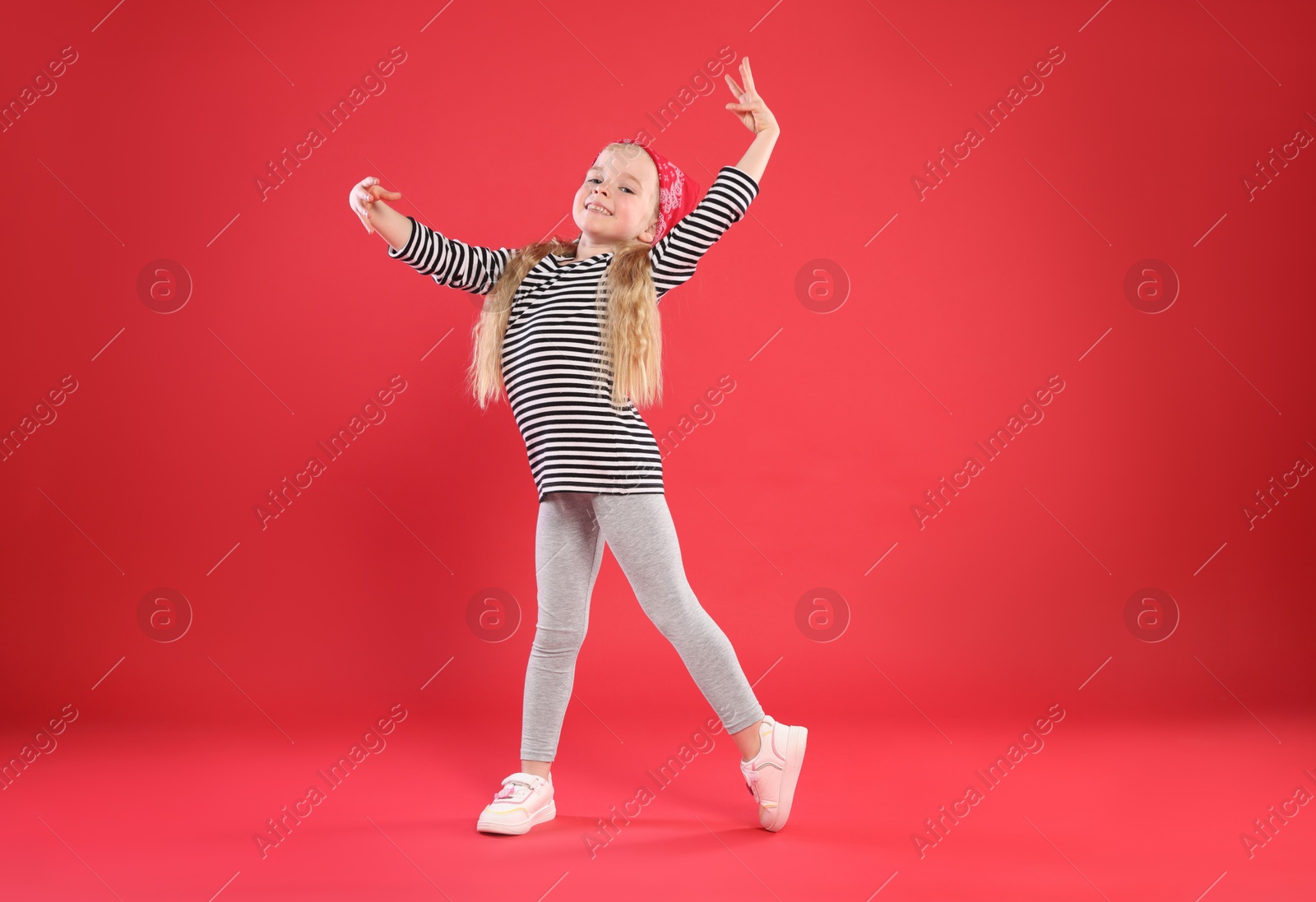 Photo of Cute little girl dancing on red background