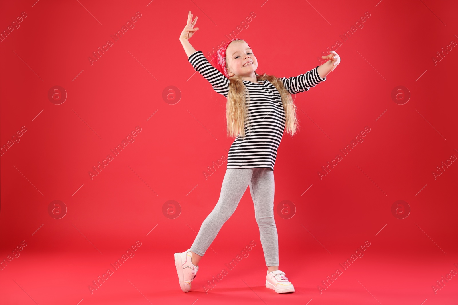 Cute little girl dancing on red background Photo of Cute little girl dancing on red background
