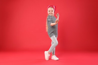 Photo of Cute little girl dancing on red background