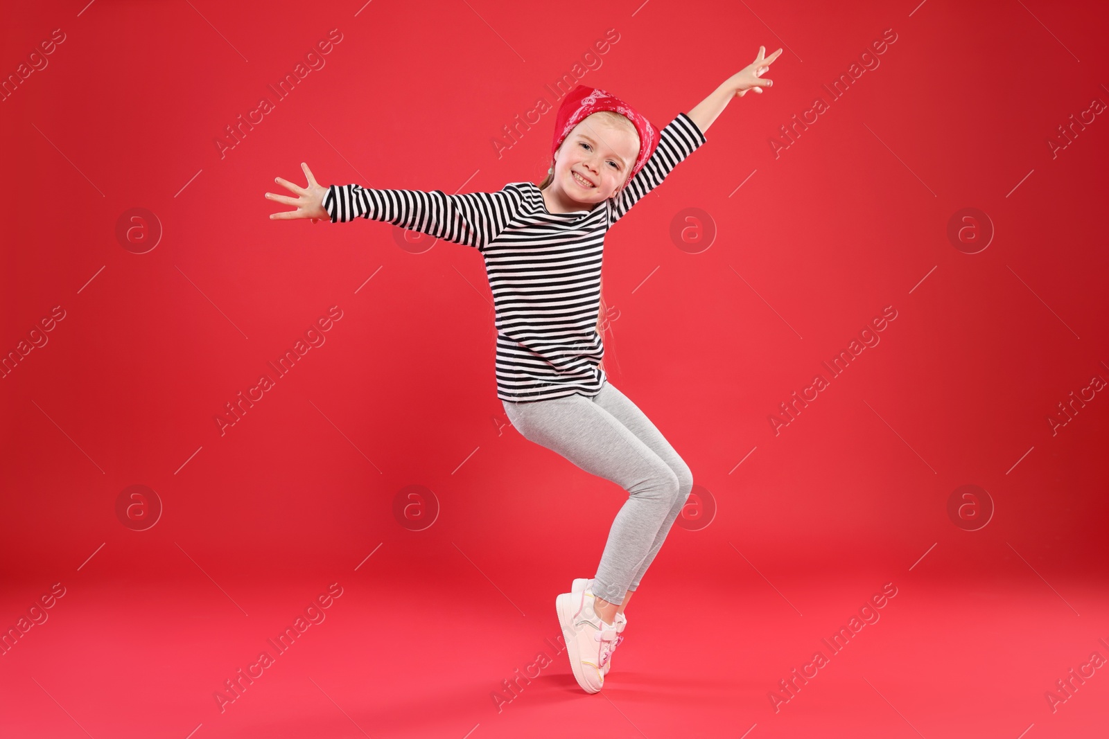 Cute little girl dancing on red background Photo of Cute little girl dancing on red background