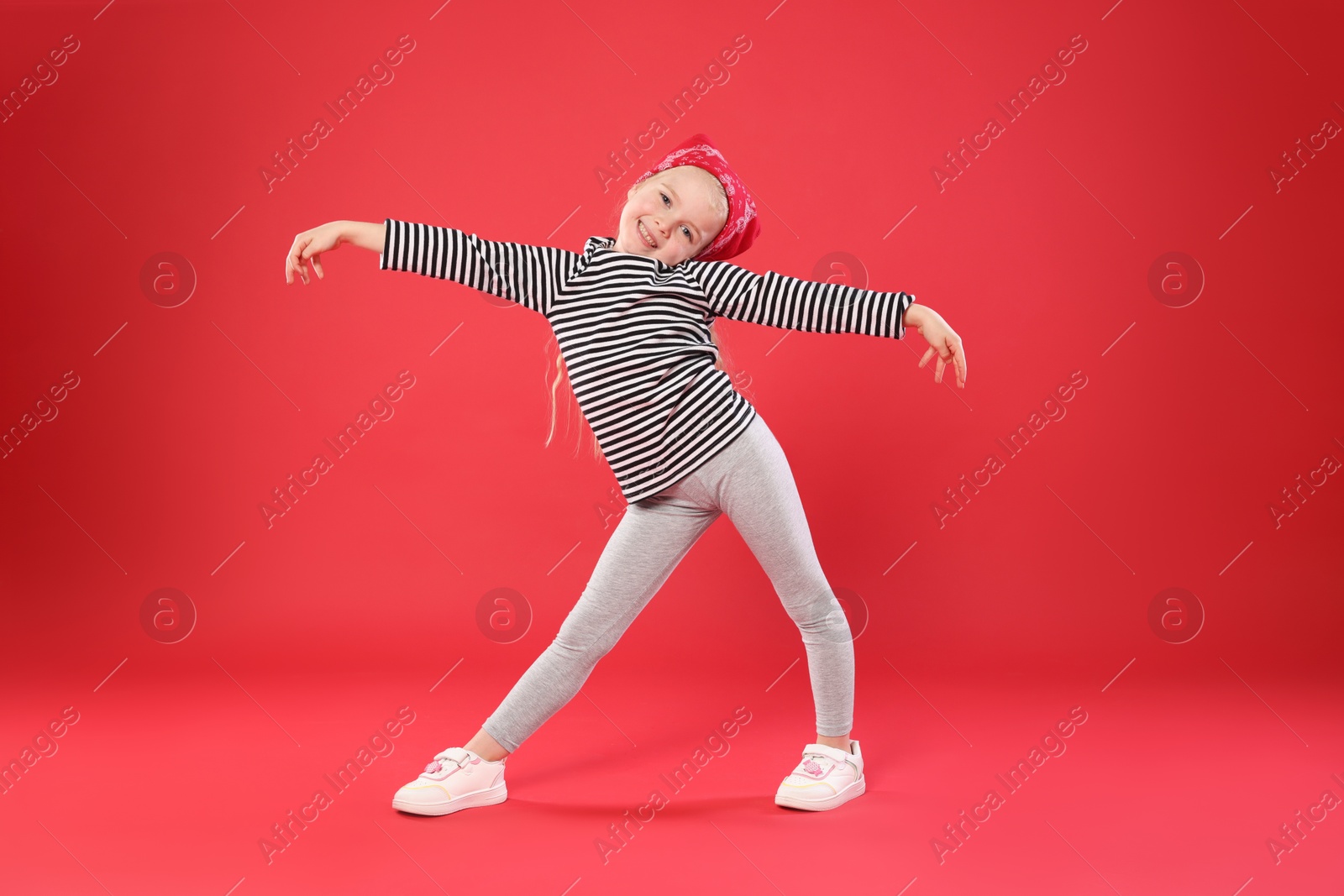 Cute little girl dancing on red background Photo of Cute little girl dancing on red background
