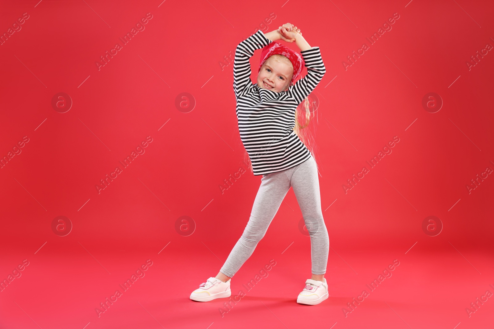 Cute little girl dancing on red background Photo of Cute little girl dancing on red background