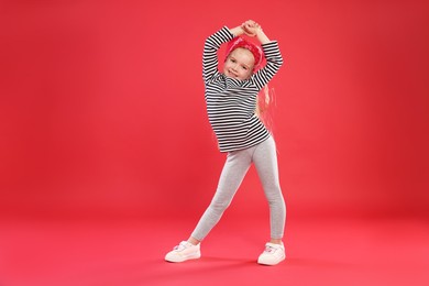 Photo of Cute little girl dancing on red background