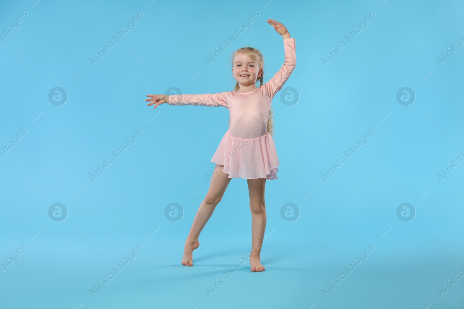 Cute little girl dancing on light blue background Photo of Cute little girl dancing on light blue background