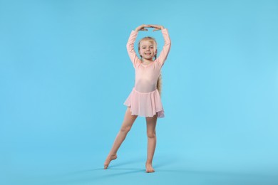 Photo of Cute little girl dancing on light blue background