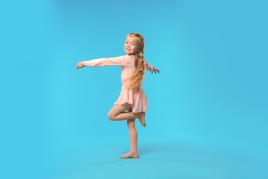 Photo of Cute little girl dancing on light blue background