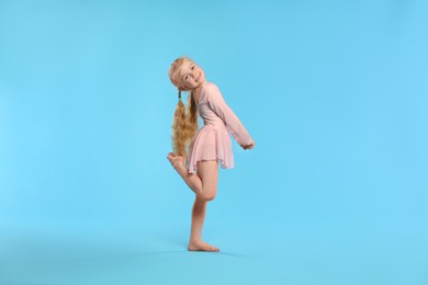 Photo of Cute little girl dancing on light blue background