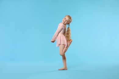 Photo of Cute little girl dancing on light blue background