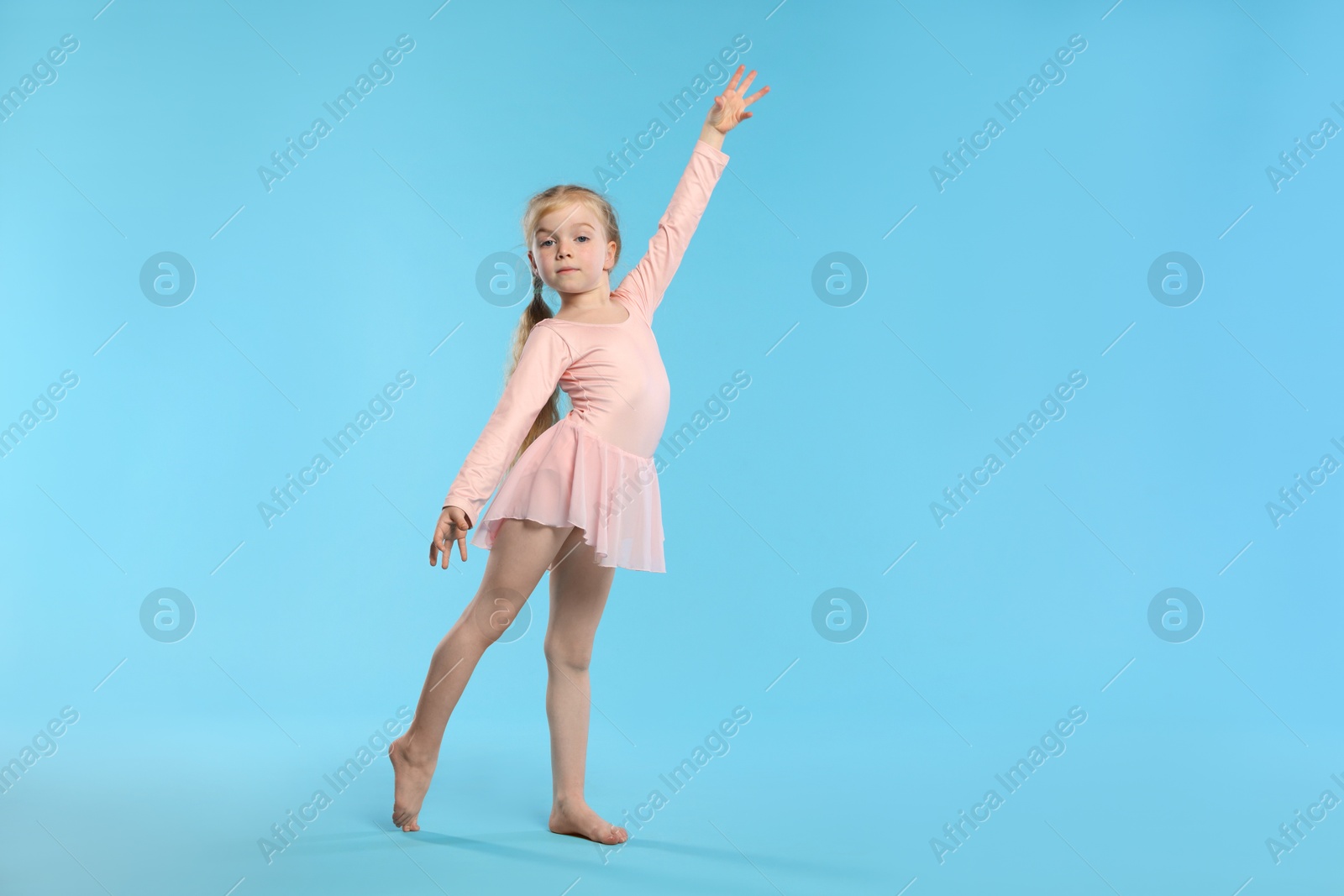 Cute little girl dancing on light blue background, space for text Photo of Cute little girl dancing on light blue background, space for text