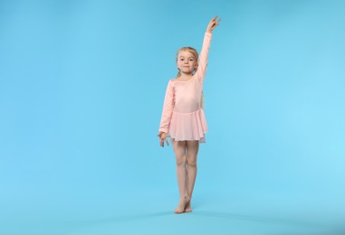 Photo of Cute little girl dancing on light blue background