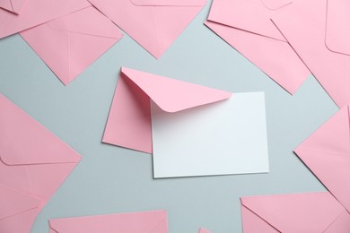Photo of Blank invitation card and envelopes on grey background, flat lay. Space for design
