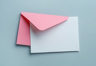 Photo of Blank invitation card and envelope on grey background, top view. Space for design
