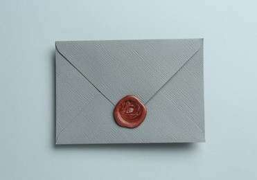 Photo of Beautiful invitation envelope with wax seal on grey background, top view