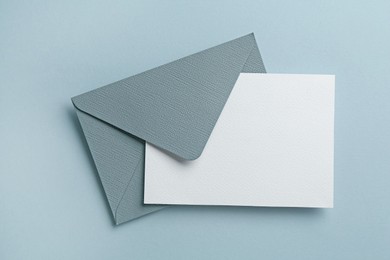 Photo of Blank invitation card and envelope on grey background, top view. Space for design