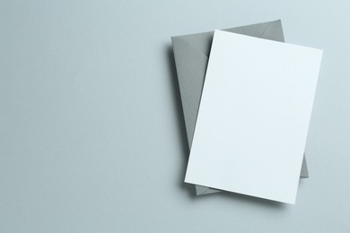 Photo of Blank invitation card and envelope on grey background, top view. Space for design