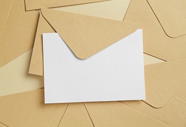 Photo of Blank invitation card and envelopes on beige background, flat lay. Space for design
