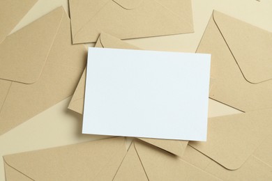 Photo of Blank invitation card and envelopes on beige background, flat lay. Space for design