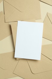 Photo of Blank invitation card and envelopes on beige background, flat lay. Space for design