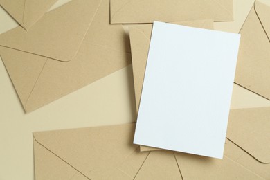 Photo of Blank invitation card and envelopes on beige background, flat lay. Space for design