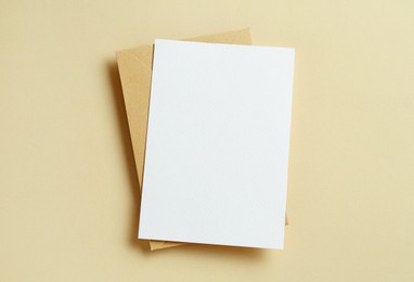 Photo of Blank invitation card and envelope on beige background, top view. Space for design