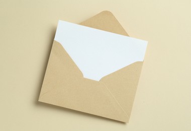 Photo of Blank invitation card and envelope on beige background, top view