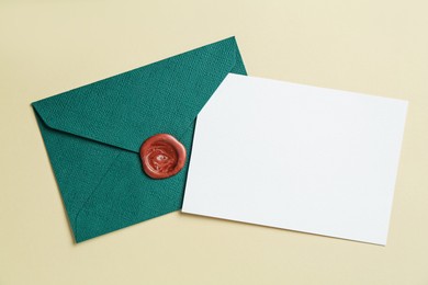 Photo of Blank invitation card and envelope on beige background, flat lay. Space for design