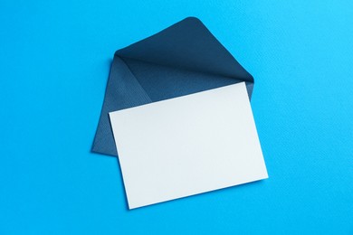Photo of Blank invitation card and envelope on light blue background, top view. Space for design