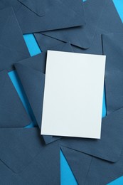 Photo of Blank invitation card and envelopes on light blue background, flat lay. Space for design
