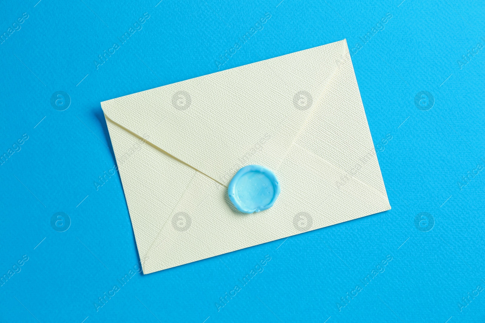 Beautiful invitation envelope with wax seal on light blue background, top view Photo of Beautiful invitation envelope with wax seal on light blue background, top view