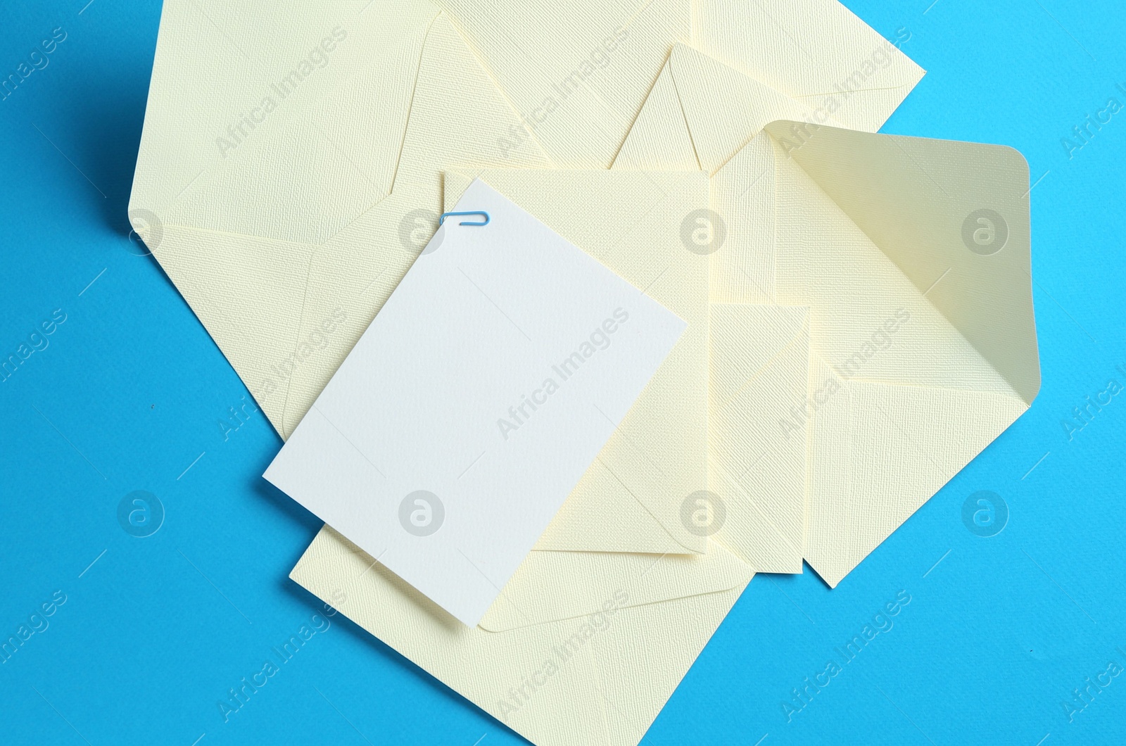 Blank invitation card and envelopes on light blue background, flat lay. Space for design Photo of Blank invitation card and envelopes on light blue background, flat lay. Space for design