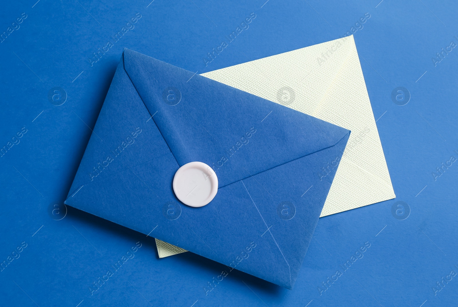 Beautiful invitation envelope and card on blue background, top view Photo of Beautiful invitation envelope and card on blue background, top view
