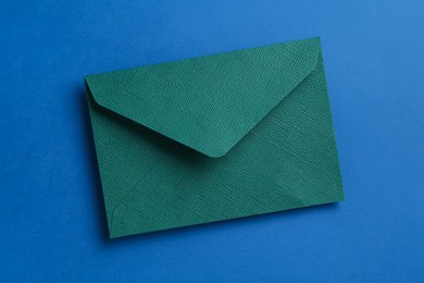 Photo of Beautiful invitation envelope on blue background, top view
