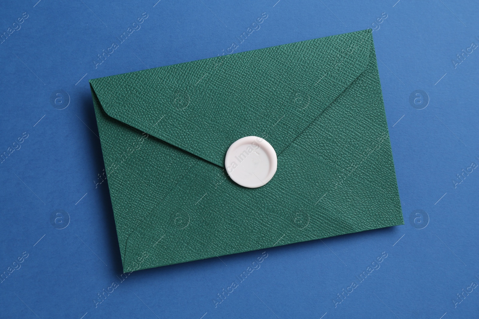 Beautiful invitation envelope with wax seal on blue background, top view Photo of Beautiful invitation envelope with wax seal on blue background, top view
